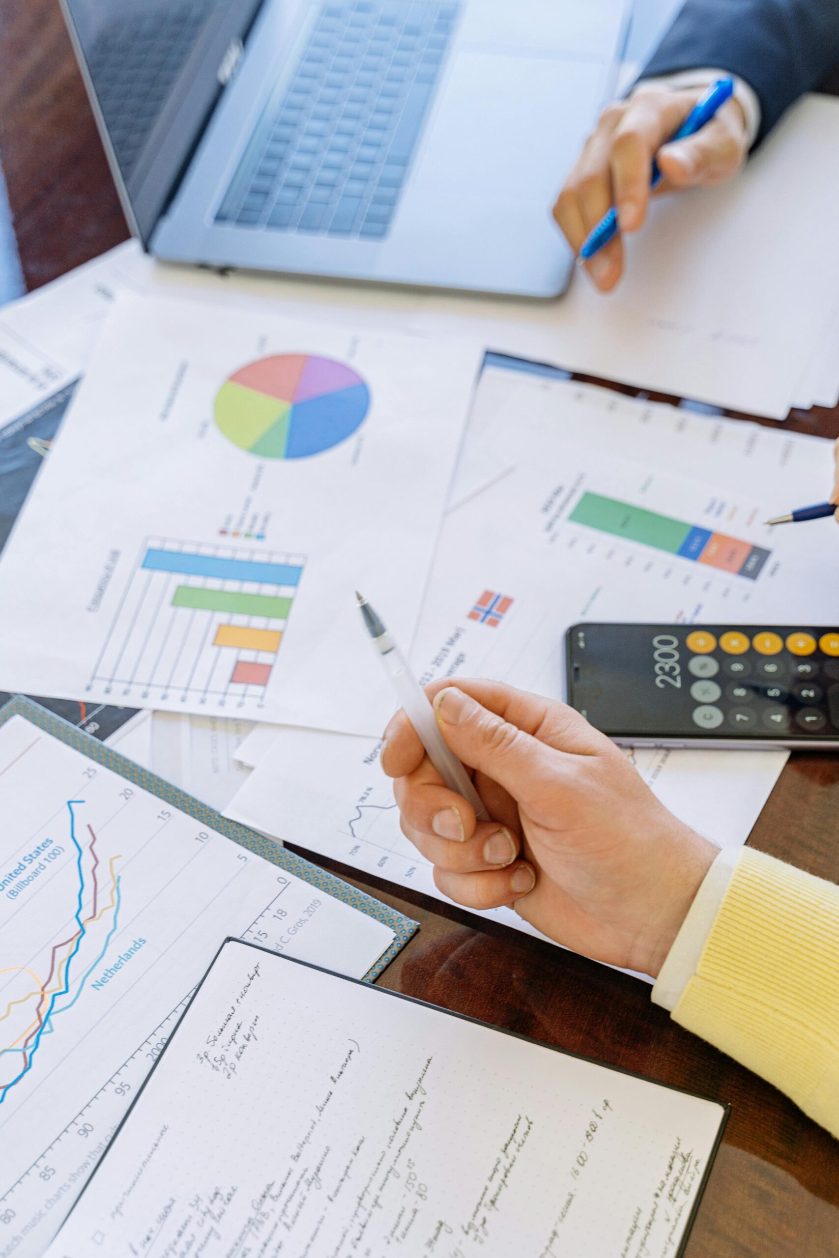 A close-up of businesspeople analyzing financial data and charts during a meeting.